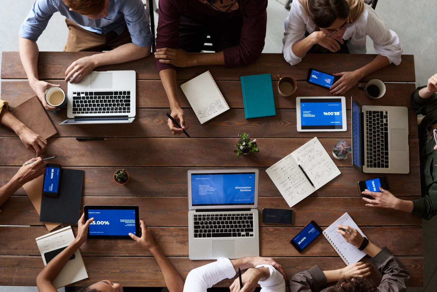 Team collaborating around a wooden table with laptops